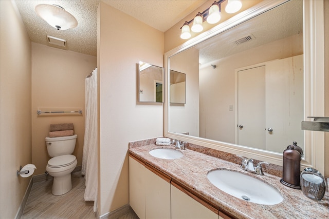 bathroom with a textured ceiling, vanity, toilet, and hardwood / wood-style flooring