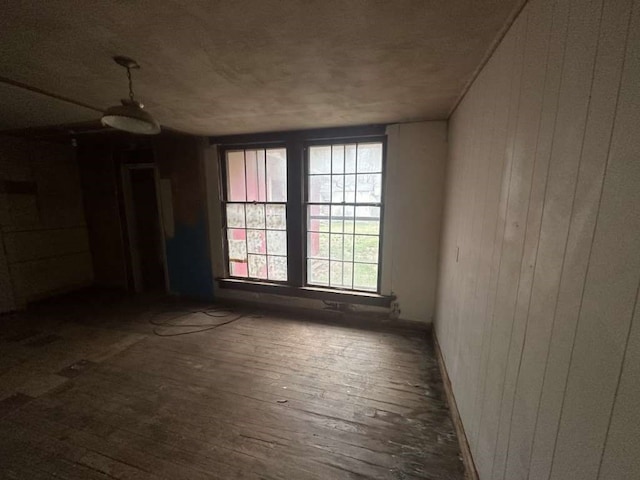 unfurnished room featuring wood walls and dark hardwood / wood-style floors