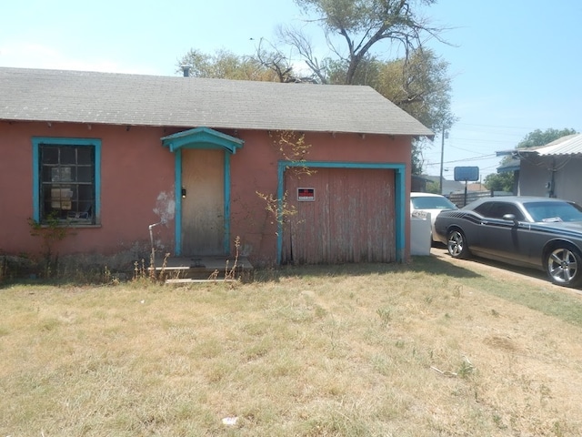 view of front of property with a garage, an outdoor structure, and a front yard