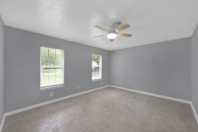 tiled empty room featuring a textured ceiling and ceiling fan