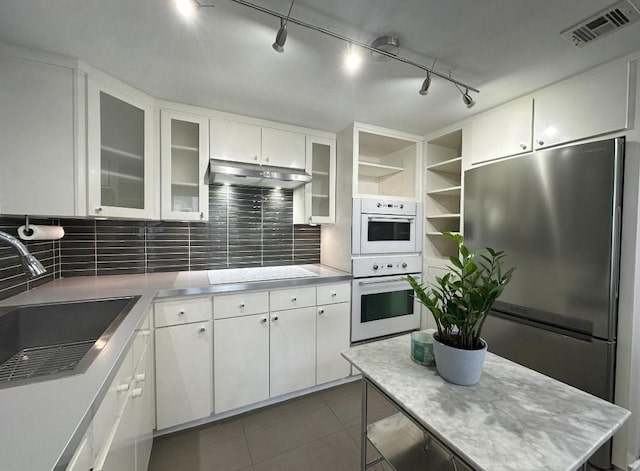 kitchen featuring sink, white cabinets, dark tile patterned flooring, and appliances with stainless steel finishes