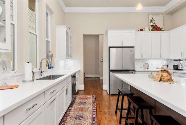 kitchen featuring a sink, ornamental molding, light countertops, backsplash, and a breakfast bar area