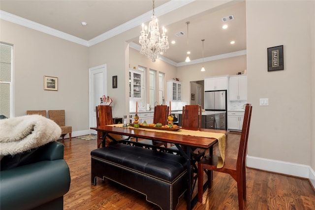dining space with crown molding, visible vents, a chandelier, wood finished floors, and baseboards