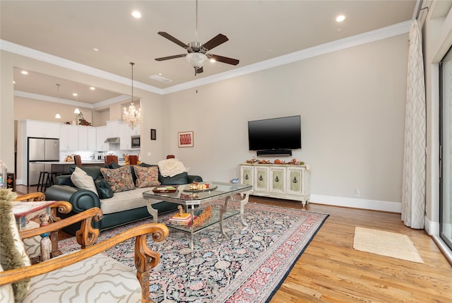 living area featuring baseboards, ornamental molding, light wood-type flooring, recessed lighting, and ceiling fan with notable chandelier