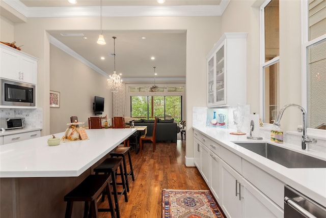 kitchen featuring crown molding, built in microwave, a breakfast bar area, dishwasher, and a sink