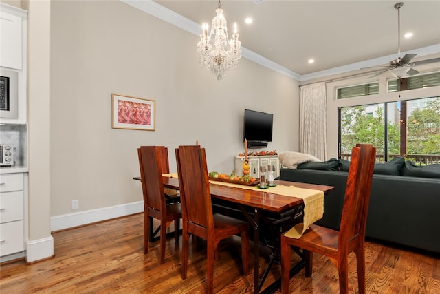 dining space with crown molding, ceiling fan with notable chandelier, recessed lighting, wood finished floors, and baseboards
