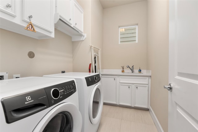 clothes washing area with baseboards, light tile patterned floors, washing machine and clothes dryer, cabinet space, and a sink