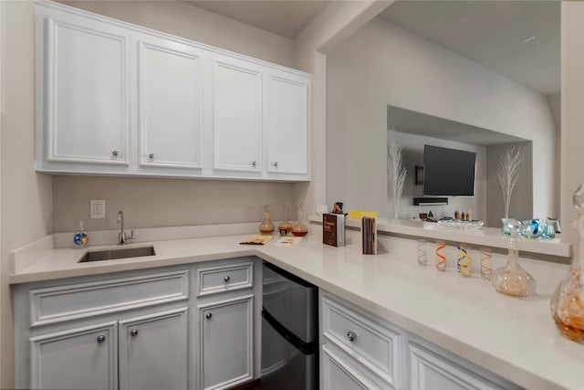 kitchen featuring light countertops, refrigerator, a sink, and white cabinetry