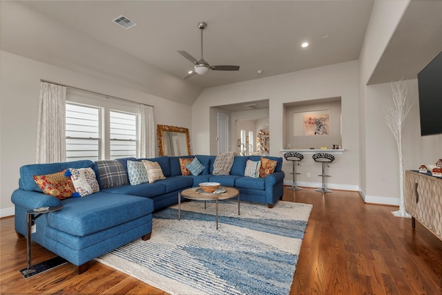 living area with visible vents, baseboards, a ceiling fan, vaulted ceiling, and wood finished floors