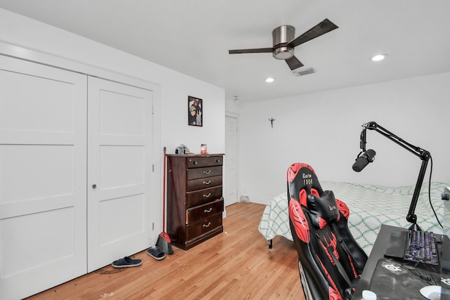 bedroom with light hardwood / wood-style flooring, ceiling fan, and a closet