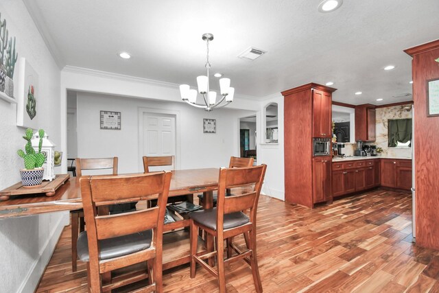 dining space featuring crown molding, an inviting chandelier, and hardwood / wood-style floors