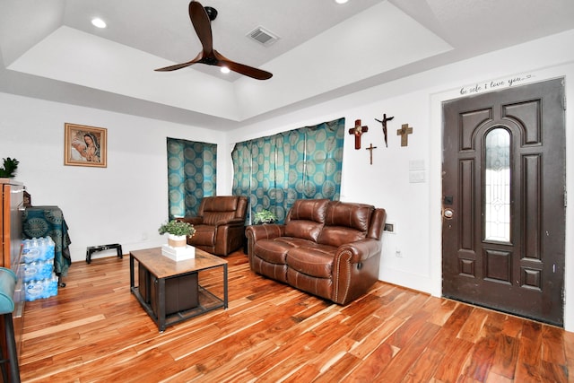 living room featuring ceiling fan, a raised ceiling, and light hardwood / wood-style flooring