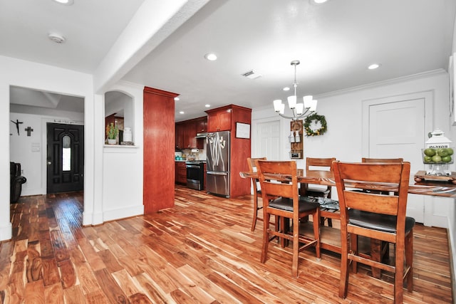 dining area with hardwood / wood-style floors, crown molding, and a notable chandelier