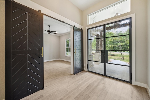 interior space with ornamental molding, a barn door, and light wood-type flooring