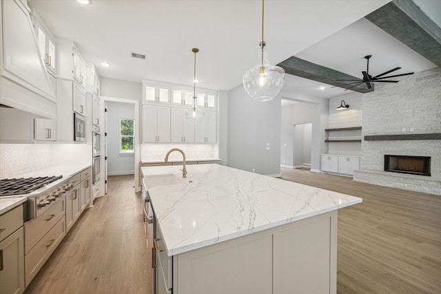 kitchen with stainless steel appliances, light stone countertops, a large island, and white cabinets