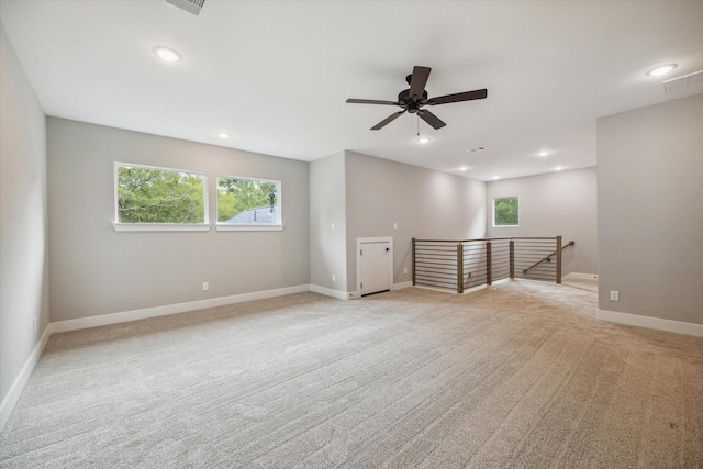 unfurnished room featuring ceiling fan, plenty of natural light, and light carpet