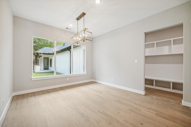 empty room featuring hardwood / wood-style flooring and a notable chandelier