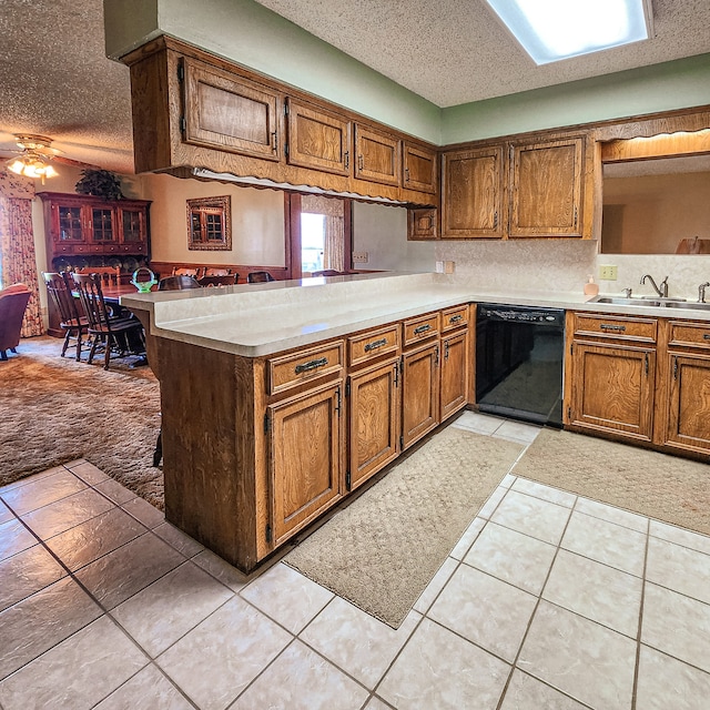 kitchen featuring kitchen peninsula, dishwasher, a textured ceiling, and sink