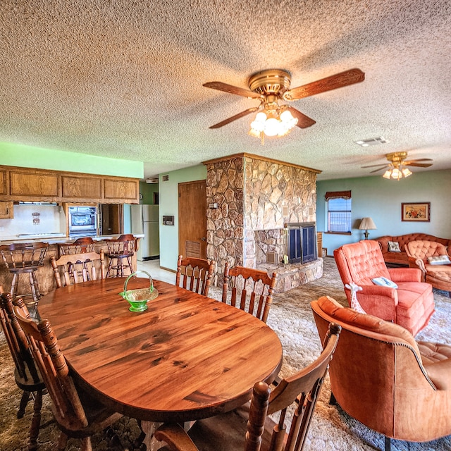 dining area featuring a textured ceiling, a fireplace, and ceiling fan