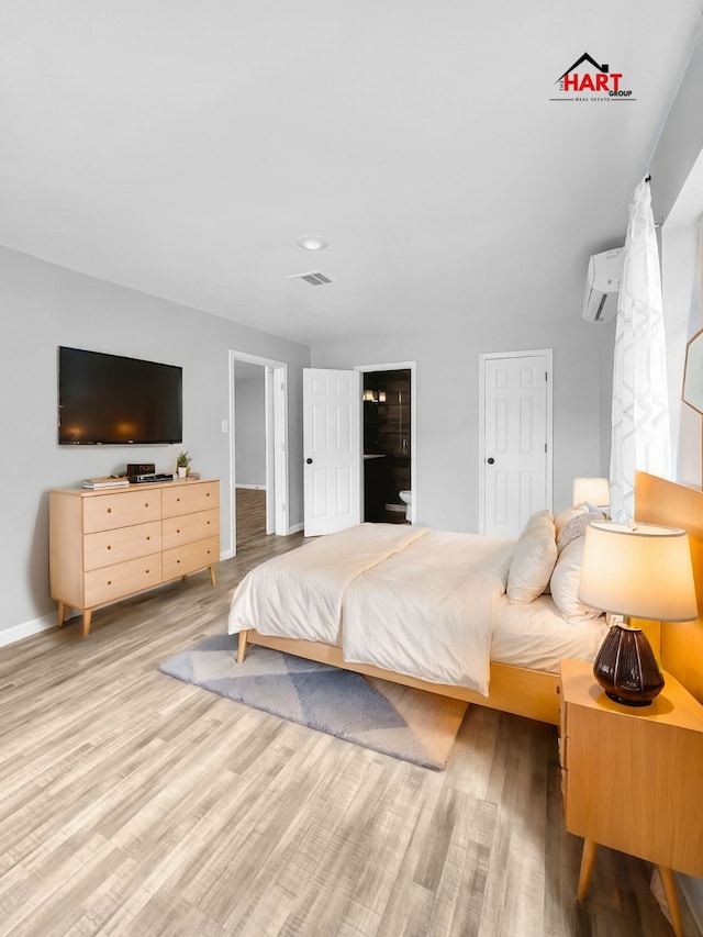 bedroom with a wall mounted AC and hardwood / wood-style flooring