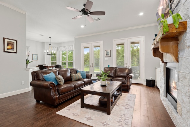 living room with french doors, a fireplace, ceiling fan with notable chandelier, crown molding, and dark hardwood / wood-style flooring