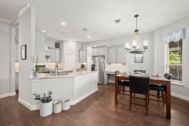 kitchen featuring appliances with stainless steel finishes, sink, backsplash, dark hardwood / wood-style flooring, and light stone counters