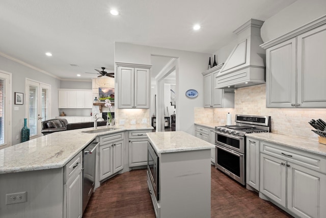 kitchen with sink, stainless steel appliances, a center island, custom range hood, and kitchen peninsula