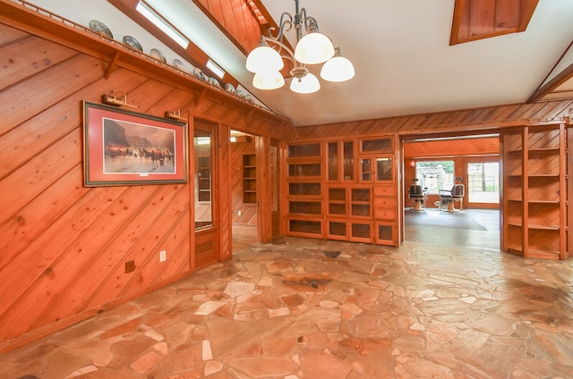 empty room featuring wooden walls, an inviting chandelier, and vaulted ceiling