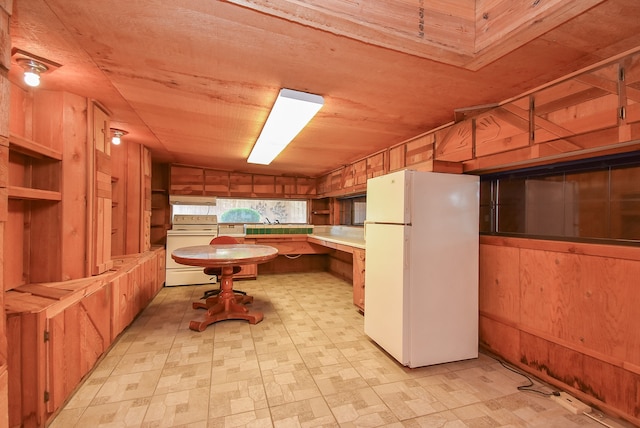 kitchen featuring white appliances, wooden walls, and lofted ceiling