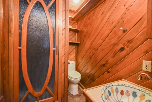 bathroom featuring vanity, toilet, and wooden walls