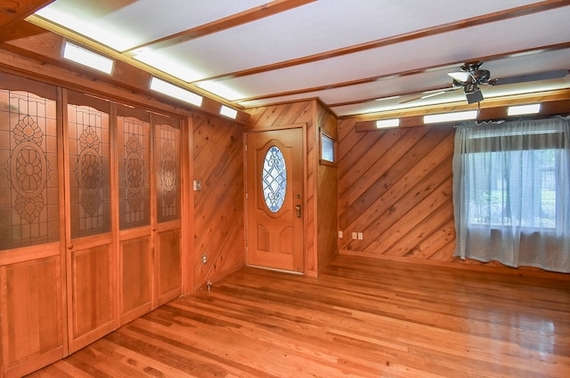 interior space featuring ceiling fan, wood walls, and wood-type flooring