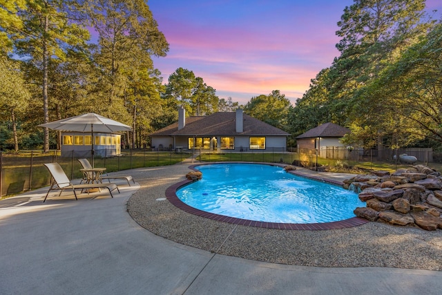 pool at dusk featuring a patio and pool water feature