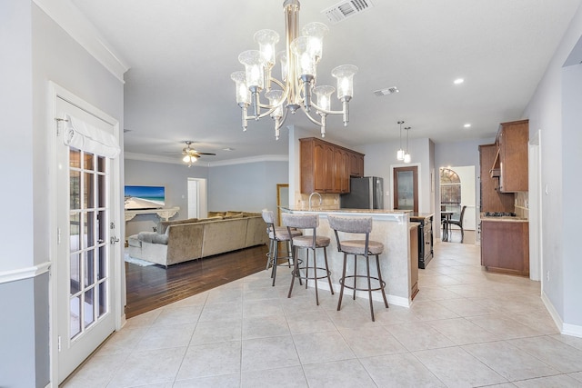 kitchen featuring light tile patterned flooring, ornamental molding, stainless steel refrigerator, and kitchen peninsula