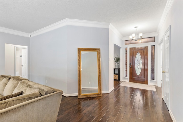 entryway with ornamental molding, dark wood-type flooring, a textured ceiling, and a chandelier