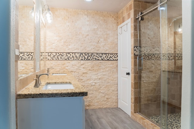 bathroom featuring wood-type flooring, a shower with door, and vanity