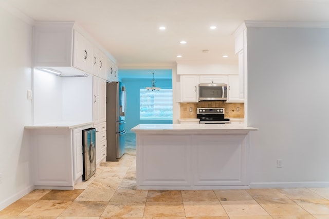 kitchen with appliances with stainless steel finishes, hanging light fixtures, kitchen peninsula, decorative backsplash, and white cabinetry