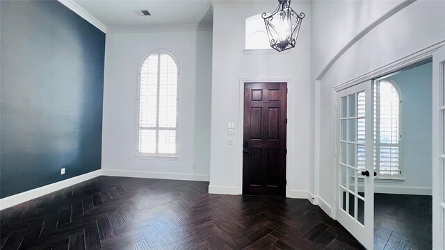 entrance foyer featuring plenty of natural light, a high ceiling, a notable chandelier, and dark parquet floors