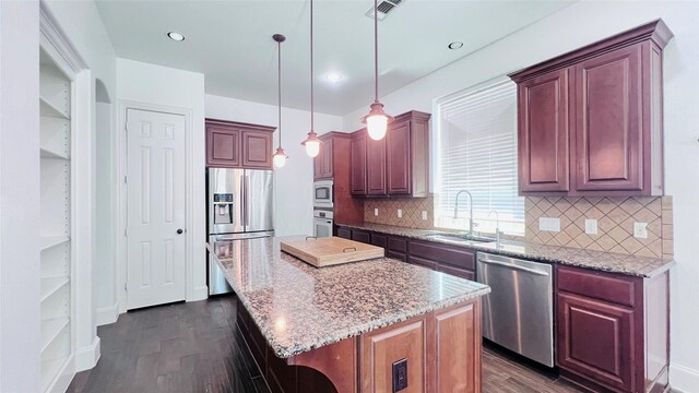 kitchen with a center island, stainless steel appliances, sink, and dark wood-type flooring