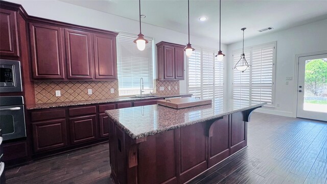 kitchen with a center island, dark hardwood / wood-style flooring, a wealth of natural light, and stainless steel appliances