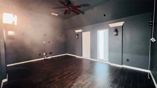 spare room featuring dark wood-type flooring, ceiling fan, and a high ceiling