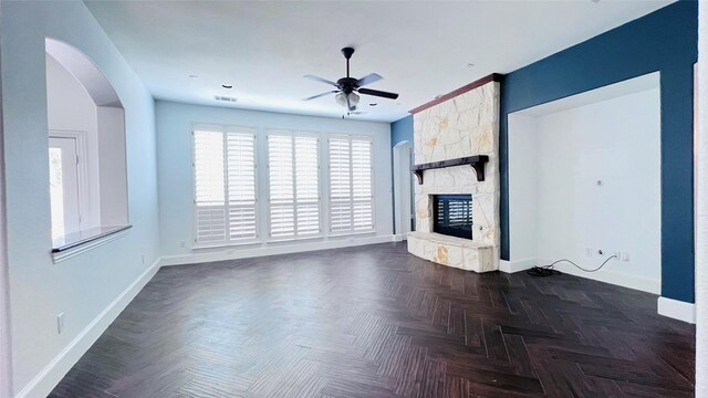 unfurnished living room with a fireplace, dark parquet flooring, and ceiling fan