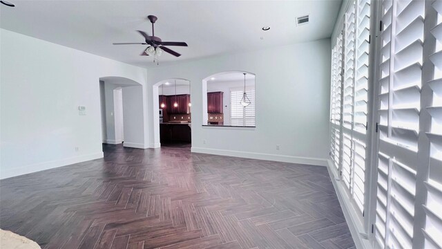 empty room with dark parquet flooring and ceiling fan