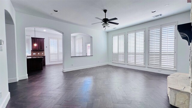 unfurnished living room with dark parquet floors and ceiling fan