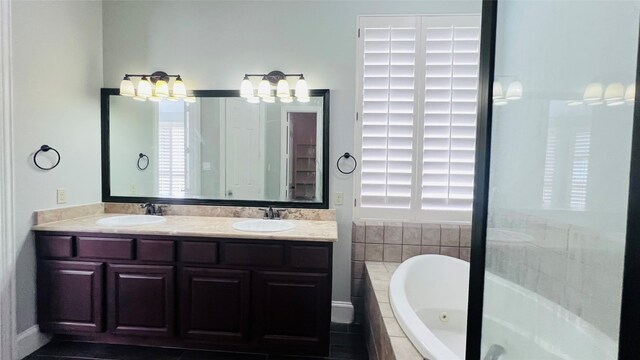 bathroom featuring tiled bath and vanity