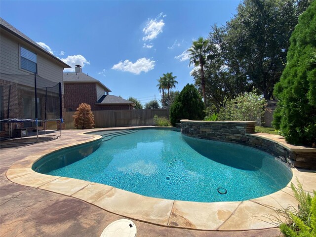 view of swimming pool with a trampoline and a patio