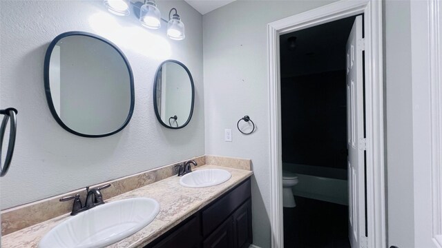 bathroom with a bath, toilet, and vanity