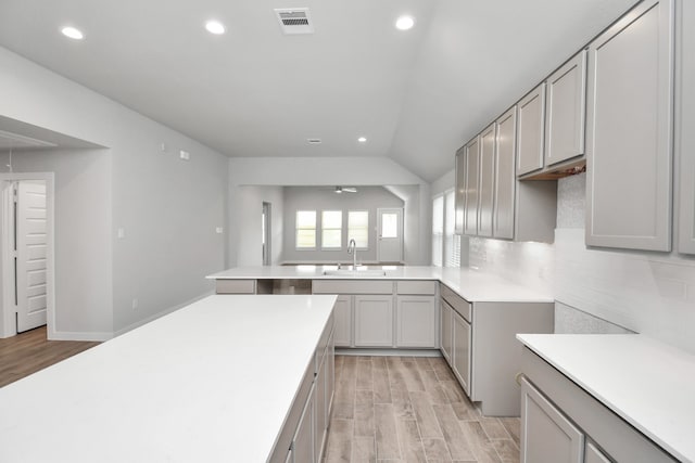 kitchen with light wood-type flooring, tasteful backsplash, sink, ceiling fan, and lofted ceiling