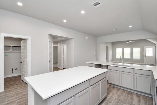 kitchen featuring a kitchen island, light hardwood / wood-style floors, sink, gray cabinets, and ceiling fan