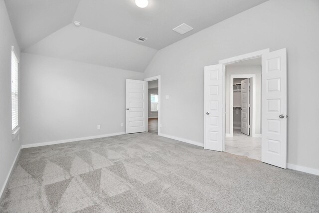 19722 Vino Vale Dr, Hockley, TX 77447 - unfurnished bedroom featuring vaulted ceiling, carpet, multiple windows, baseboards, and a walk in closet