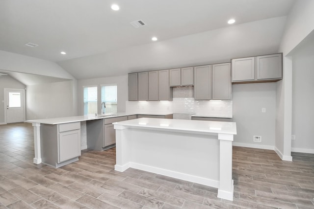 19722 Vino Vale Dr, Hockley, TX 77447 - kitchen featuring gray cabinetry, vaulted ceiling, a sink, light wood finished floors, and recessed lighting